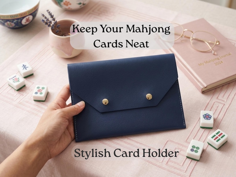 May include: A navy blue card holder with gold button closures. The text "Keep Your Mahjong Cards Neat" and "Stylish Card Holder" are visible. Mahjong tiles and a pink journal are also present.