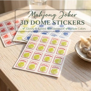 May include: Sheets of 3D dome stickers for Mahjong Joker, featuring glossy, raised, and waterproof designs in multiple colors. The stickers have a red border and a yellow and green design. The text "JOKER" is visible.