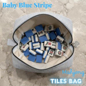 May include: A baby blue striped Mahjong tiles bag, open to reveal blue and white tiles. The bag has a zipper closure and a small handle. The text "Baby Blue Stripe" and "Mahjong TILES BAG" are visible.