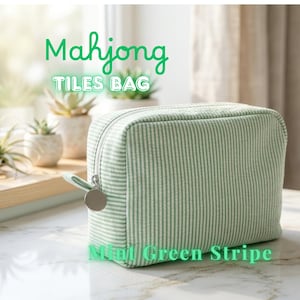 May include: A mint green striped Mahjong Tiles Bag with a zipper closure and a silver-tone charm. The bag is rectangular and sits on a marble surface. Text on the bag reads "Mahjong Tiles Bag" and "Mint Green Stripe."