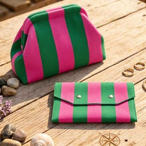 May include: A structured pouch with a kiss-lock closure and a matching rectangular envelope-style wallet, both featuring a vibrant vertical striped pattern in alternating shades of bright pink and forest green, crafted from a textured fabric material.
