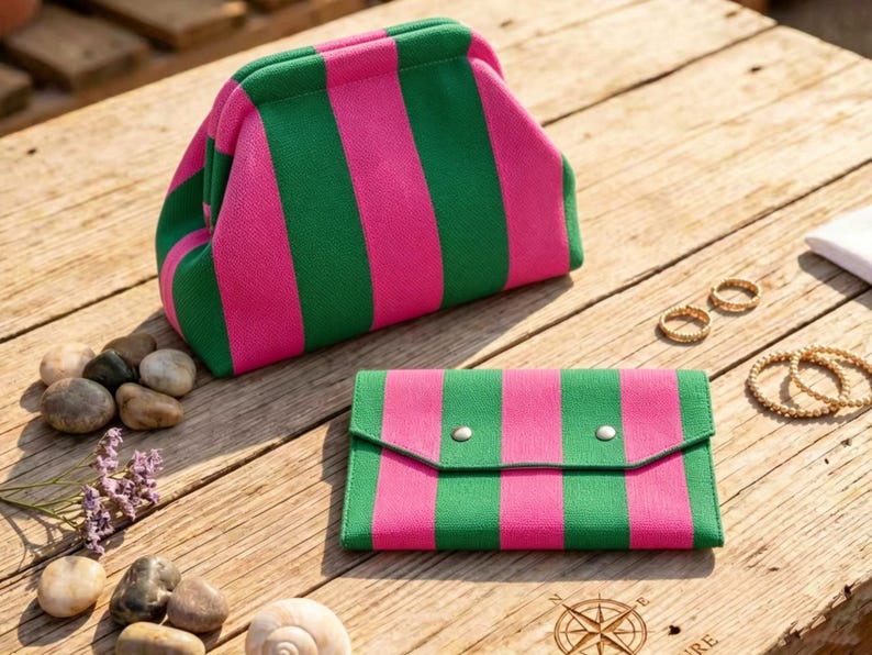 May include: A structured pouch with a kiss-lock closure and a matching rectangular envelope-style wallet, both featuring a vibrant vertical striped pattern in alternating shades of bright pink and forest green, crafted from a textured fabric material.