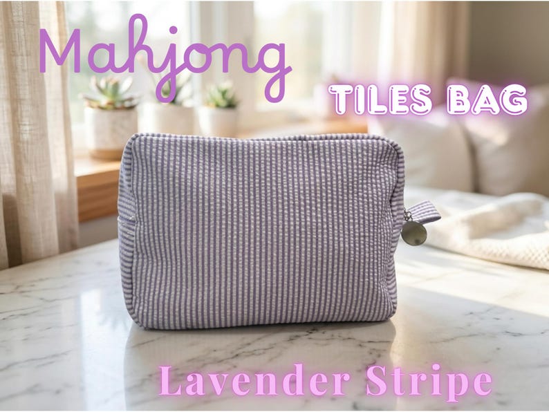 May include: A lavender and white striped Mahjong Tiles Bag. The rectangular bag has a zipper closure with a metal charm and a small fabric loop. The text "Mahjong Tiles Bag" and "Lavender Stripe" are displayed on the image.