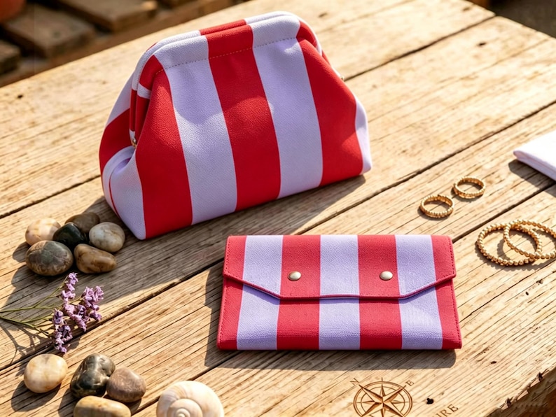May include: A red and light purple striped frame pouch and a matching rectangular envelope-style wallet with two silver-toned snap closures. The items feature a bold vertical stripe pattern in a vibrant red and a soft, muted light purple color.