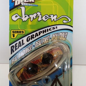 May include: A Tech Deck wakeboard toy in its original packaging. The packaging is blue and green with the words "Tech Deck Wakeboard" and "Obrien" printed on it. The toy includes a small wakeboard with black bindings and a stand.