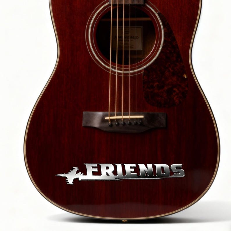 May include: Acoustic guitar with a dark red-brown finish. The guitar features a silver "FRIENDS" logo. The strings are visible, and the sound hole is centered. The pickguard has a patterned design.
