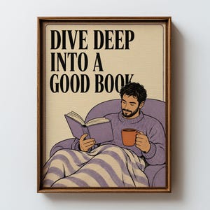 May include: A framed wall art print featuring a bearded person in a purple sweater sitting in a purple armchair, reading a book and holding an orange mug. The text DIVE DEEP INTO A GOOD BOOK is printed in black at the top on a cream background.
