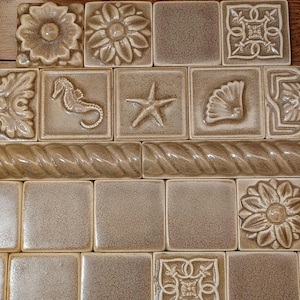 May include: A set of three ceramic canisters with lids. The canisters are white with a blue floral pattern. The largest canister is 8 inches tall, the medium is 6 inches, and the smallest is 4 inches.