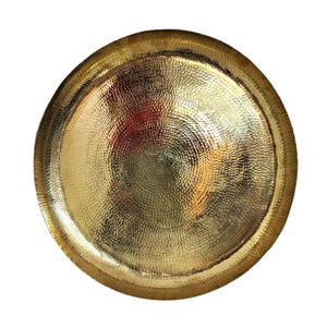 May include: A round, hammered gold-colored metal tray. The tray has a textured surface with a dimpled pattern. The rim of the tray is slightly raised. The tray is a decorative item.