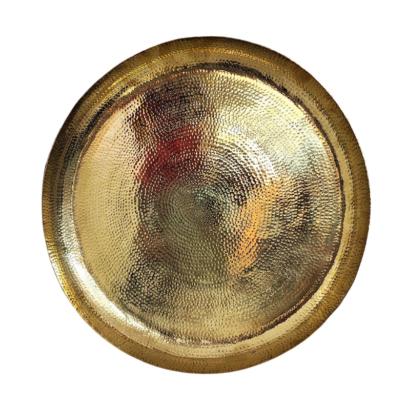 May include: A round, hammered gold-colored metal tray. The tray has a textured surface with a dimpled pattern. The rim of the tray is slightly raised. The tray is a decorative item.
