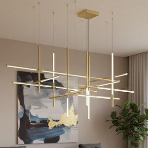 May include: Modern gold-toned chandelier with a geometric design. The fixture features multiple horizontal and vertical light bars, creating a layered effect. The light bars emit a bright, white light, illuminating the room. The chandelier hangs from the ceiling, adding a contemporary touch to the space.