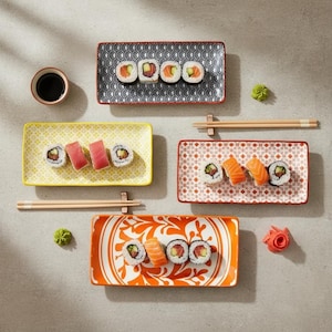 May include: Overhead shot of sushi rolls on decorative rectangular plates. The plates have various patterns and colors, including black and white waves, yellow with a geometric design, and orange with a floral design. Chopsticks, soy sauce, and wasabi are also present.