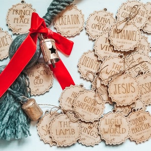 May include: A collection of wooden ornaments with religious text and scripture verses. The ornaments are decorated with a floral design and have a rustic look. The ornaments are tied with twine and are ready to be hung on a Christmas tree.