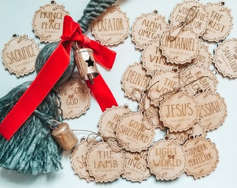 May include: A collection of wooden ornaments with religious text and scripture verses. The ornaments are decorated with a floral design and have a rustic look. The ornaments are tied with twine and are ready to be hung on a Christmas tree.