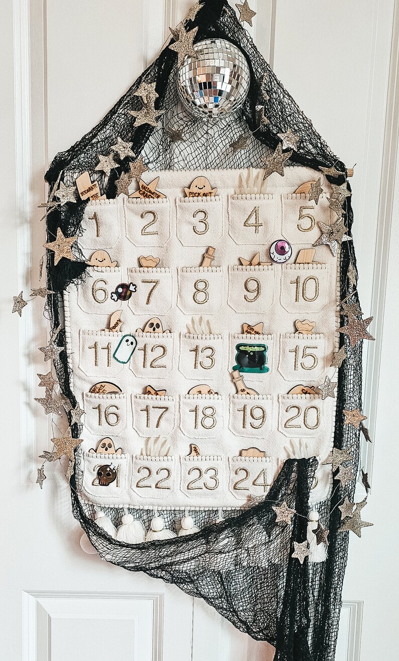 Peut inclure: Un calendrier de l'avent en feutre blanc avec 24 poches, chacune avec une image diff&eacute;rente sur le th&egrave;me d'Halloween. Le calendrier est d&eacute;cor&eacute; d'&eacute;toiles dor&eacute;es scintillantes et d'un tissu en maille noire.
