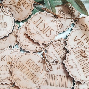 May include: A collection of wooden ornaments with various Christian-themed phrases and scripture verses. The ornaments are decorated with a floral design and have a rustic, natural look.