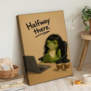 May include: A canvas print featuring a green frog with black hair, seated at a desk with a laptop and two coffee cups. The frog is holding a phone. The text "Halfway there." is above the frog.