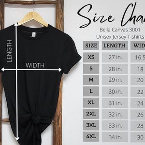 Może przedstawiać: Czarna koszulka unisex Bella Canvas 3001 zawieszona na drewnianej drabinie. Obraz zawiera tabelę rozmiar&oacute;w z wymiarami w cm dla rozmiar&oacute;w XS do 4XL. Tabela zawiera długość i szerokość dla każdego rozmiaru.
