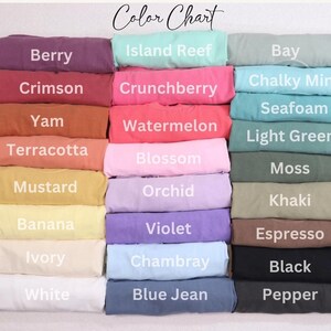 May include: A colour chart displaying folded t-shirts in various shades. The colours are labelled: Berry, Crimson, Yam, Terracotta, Mustard, Banana, Ivory, White, Island Reef, Crunchberry, Watermelon, Blossom, Orchid, Violet, Chambray, Blue Jean, Bay, Chalky Mint, Seafoam, Light Green, Moss, Khaki, Espresso, Black, and Pepper.