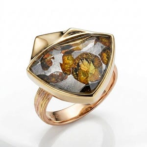 Könnte beinhalten: Ein Ring mit einem großen, dreieckigen Stein mit metallisch silbernem und bernsteinfarbenem Inneren. Der Stein ist in einen polierten goldfarbenen Rahmen gefasst. Die Ringschiene besteht aus texturiertem Rosé-, Gelb- und Weißgold mit S925-Stempel.