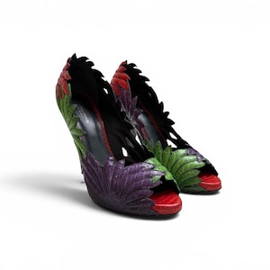 May include: High-heeled shoes with a distinctive leaf pattern. The shoes are a mix of red, green, purple, and black. The open-toe design and stiletto heels contribute to the shoes' elegant look. The shoes are a stylish fashion item.