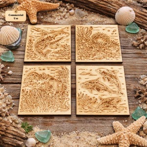 May include: Four square wooden coasters with engraved ocean-themed designs. Each coaster features a different marine life scene: a shark, coral, a fish, and dolphins. The coasters are light brown and set on a wooden surface with sand and seashells.