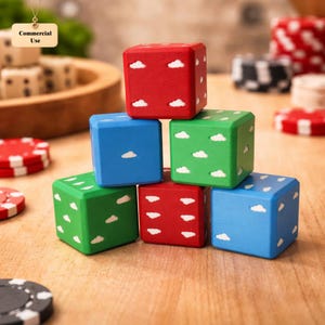 Könnte beinhalten: Ein Stapel von sechs bunten Würfeln, jeder in einer anderen Farbe bemalt: rot, blau und grün. Jeder Würfel hat weiße Wolkenmuster. Pokerchips und andere Würfel sind im Hintergrund zu sehen, was auf ein Spiel- oder Glücksspielthema hindeutet.