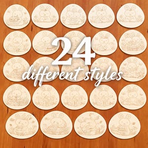 Puede incluir: Un conjunto de 24 adornos de madera con forma de huevo de Pascua, cada uno con un diseño de conejito grabado único. Los adornos están dispuestos sobre una superficie de madera. El texto "24 different styles" se muestra en el centro.