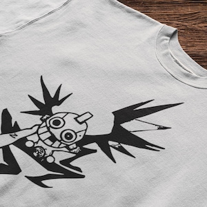 Pode incluir: Uma t-shirt de gola redonda cinzenta clara com uma impressão gráfica preta de uma personagem estilizada e caricata com grandes olhos circulares, uma crista e apêndices afiados em forma de asas, numa pose dinâmica com um braço estendido.