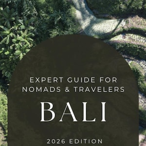 Op de afbeelding: Een reisgidsomslag met het woord "BALI" in grote witte letters. De tekst "EXPERT GUIDE FOR NOMADS & TRAVELERS" staat boven het woord "BALI". De editie "2026" staat onderaan. De achtergrond toont een groen landschap.