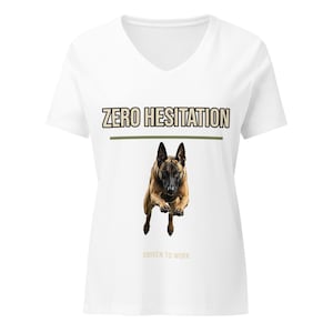 Puede incluir: Una camiseta negra con cuello en V que presenta un gráfico de un perro pastor belga malinois marrón y negro en pleno salto. Sobre el perro, el texto dice ZERO HESITATION en letras blancas, y debajo, el texto dice DRIVEN TO WORK en letras blancas.