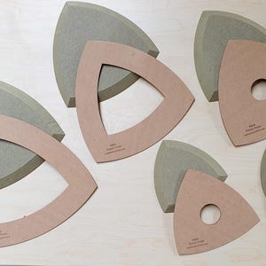 May include: A selection of tan and grey triangular wooden forms. Some have a triangle cut out of the centre, others a circular hole. The text "Rapid Pattern Finder" is printed on some of the shapes.