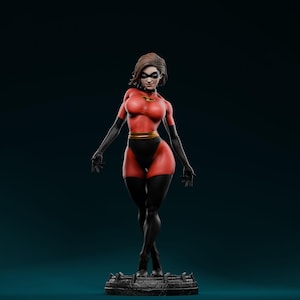May include: A figurine of a female superhero in a red and black costume with a gold belt. The figure has short brown hair, a black mask, and black gloves. The superhero is standing on a textured base.