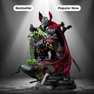 May include: A detailed Spawn action figure statue featuring a dark armored character with a flowing red cape, holding a large sword with green glowing accents. The figure stands on a rocky base with chains and bats, labeled Bestseller and Popular Now.