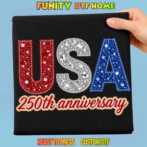 May include: A black fabric transfer featuring the letters USA in red, white, and blue rhinestones. Below the letters, the text 250th anniversary is written in a red script font with a gold outline. The top text reads FUNITY DTF HOME.