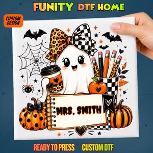 May include: A white DTF transfer sheet featuring a cartoon ghost with a leopard and checkered bow, holding a coffee cup. It includes a notepad labeled MRS. SMITH, pumpkins, pencils, a spider web, and bats in orange, black, and white colors.