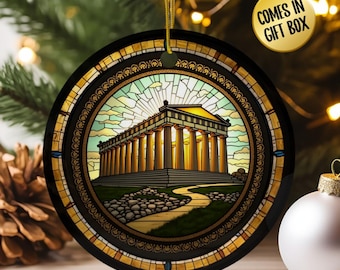 May include: Round Christmas ornament with a stained-glass design featuring a classical building with columns. The ornament has a black border with gold accents and a gold hanging string. The text "COMES IN GIFT BOX" is in a yellow circle.