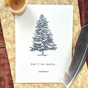 May include: A white card with a detailed illustration of a pine tree, accompanied by the text "don't be hasty." and "treebeard." A feather quill and a candle sit nearby on a textured, aged paper.