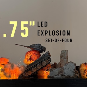 May include: A set of four .75 inch LED explosion effects for miniature models. The set features orange and yellow glowing light effects designed to simulate fire and smoke, displayed alongside a miniature tank and gray rubble ruins.