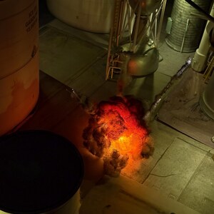 Pu&ograve; includere: Un diorama in miniatura che mostra una scena di lancio di un razzo con un effetto di esplosione arancione e rosso brillante alla base. Il modello include una struttura metallica del razzo, serbatoi cilindrici e componenti industriali.