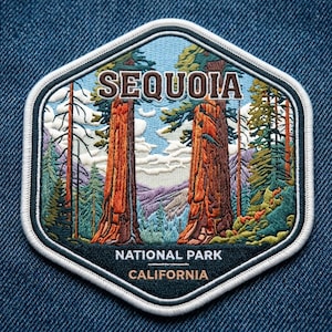 May include: A hexagonal embroidered patch featuring a landscape of two large sequoia trees in the foreground with mountains and clouds in the background. The text reads SEQUOIA NATIONAL PARK CALIFORNIA in white and orange lettering on a dark border.