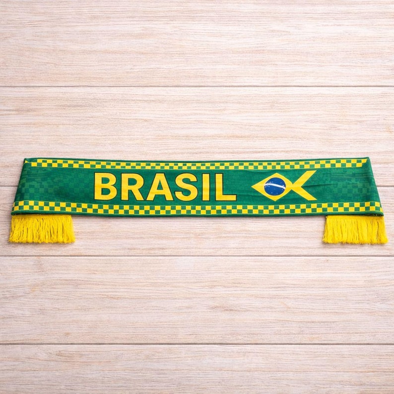 Peut inclure: &Eacute;charpe verte avec le mot "BRASIL" en lettres jaunes. L'&eacute;charpe pr&eacute;sente le drapeau br&eacute;silien et des franges jaunes aux deux extr&eacute;mit&eacute;s. L'&eacute;charpe est en tissu textur&eacute;.