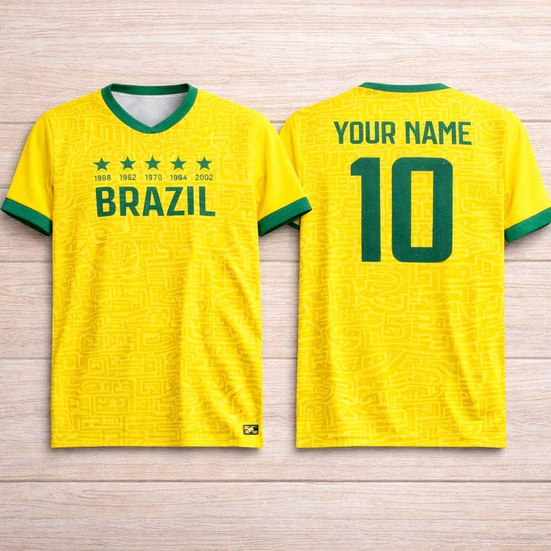 Peut inclure: Un maillot de football jaune du Br&eacute;sil avec des bordures vertes. Il affiche "BRAZIL" et les ann&eacute;es 1968, 1992, 1970, 1994 et 2002. Le dos porte "YOUR NAME" au-dessus du num&eacute;ro 10 en vert.