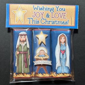May include: A Christmas-themed gift set featuring three wrapped items with illustrations of the Nativity scene. The packaging includes the text "Wishing You JOY & LOVE This Christmas!" and images of Joseph, Mary, and baby Jesus.