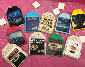 Può includere: Una collezione di 10 etichette per il tè a tema libro, ognuna con una diversa copertina di libro. Le etichette sono fatte di carta e hanno un aspetto vintage. I libri includono "The Great Gatsby", "Gone With The Wind", "The Hunger Games", "Wuthering Heights", "Roots", "The Woman in Cabin 10", "City of Endless Night", "All the Light We Cannot See", "The Couple Next Door" e "Wild".