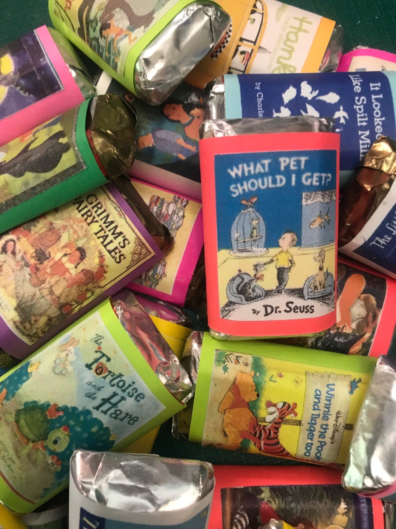 K&ouml;nnte beinhalten: Eine Sammlung von verpackten Schokoladenriegeln mit bunten Buchumschl&auml;gen, die beliebte Kindergeschichten zeigen, darunter "Welches Haustier soll ich mir holen?" von Dr. Seuss, "Die Schildkr&ouml;te und der Hase", "Winnie Puuh und Tigger auch" und "Grimms M&auml;rchen".