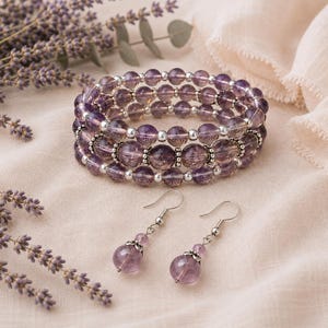 May include: A multi-strand bracelet made of translucent purple amethyst beads and small silver-toned metal spacers, accompanied by a pair of matching drop earrings featuring single amethyst beads and silver-toned metal hooks and bead caps.