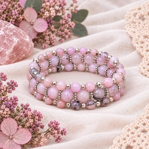 May include: A multi-strand wrap bracelet featuring smooth, round pink gemstone beads interspersed with small, reflective silver-toned metal spacer beads. The bracelet displays a gradient of pink shades, ranging from pale to deep rose, with some beads showing natural dark inclusions.