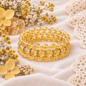 May include: A multi-strand bracelet featuring translucent yellow citrine gemstone beads interspersed with small, polished silver-tone metal spacer beads and decorative, textured silver-tone metal accent beads arranged in a repeating pattern.