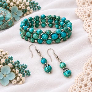 May include: A multi-strand stretch bracelet and a pair of matching drop earrings featuring round turquoise-colored beads with dark veining, interspersed with small silver-toned metal spacer beads and decorative filigree metal bead caps.